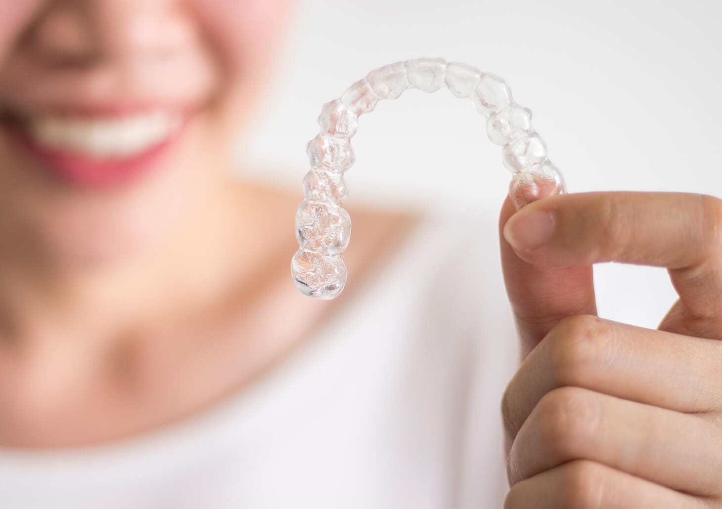 closeup of a person holding up a clear aligner